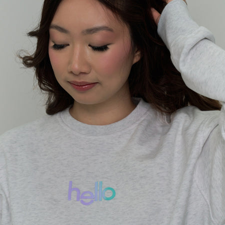 close-up of woman wearing hello products grey “everyday yay” sweater with hello logo