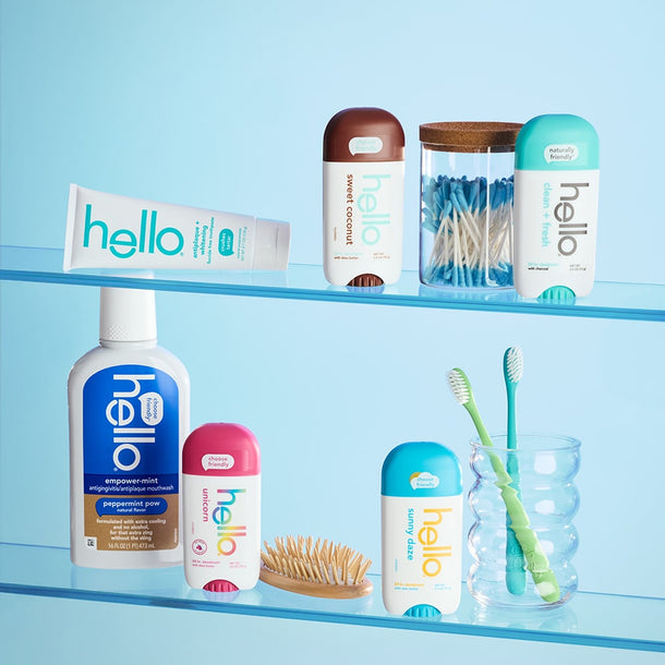 Collection of 'hello' branded dental care products on a glass shelf against a blue background