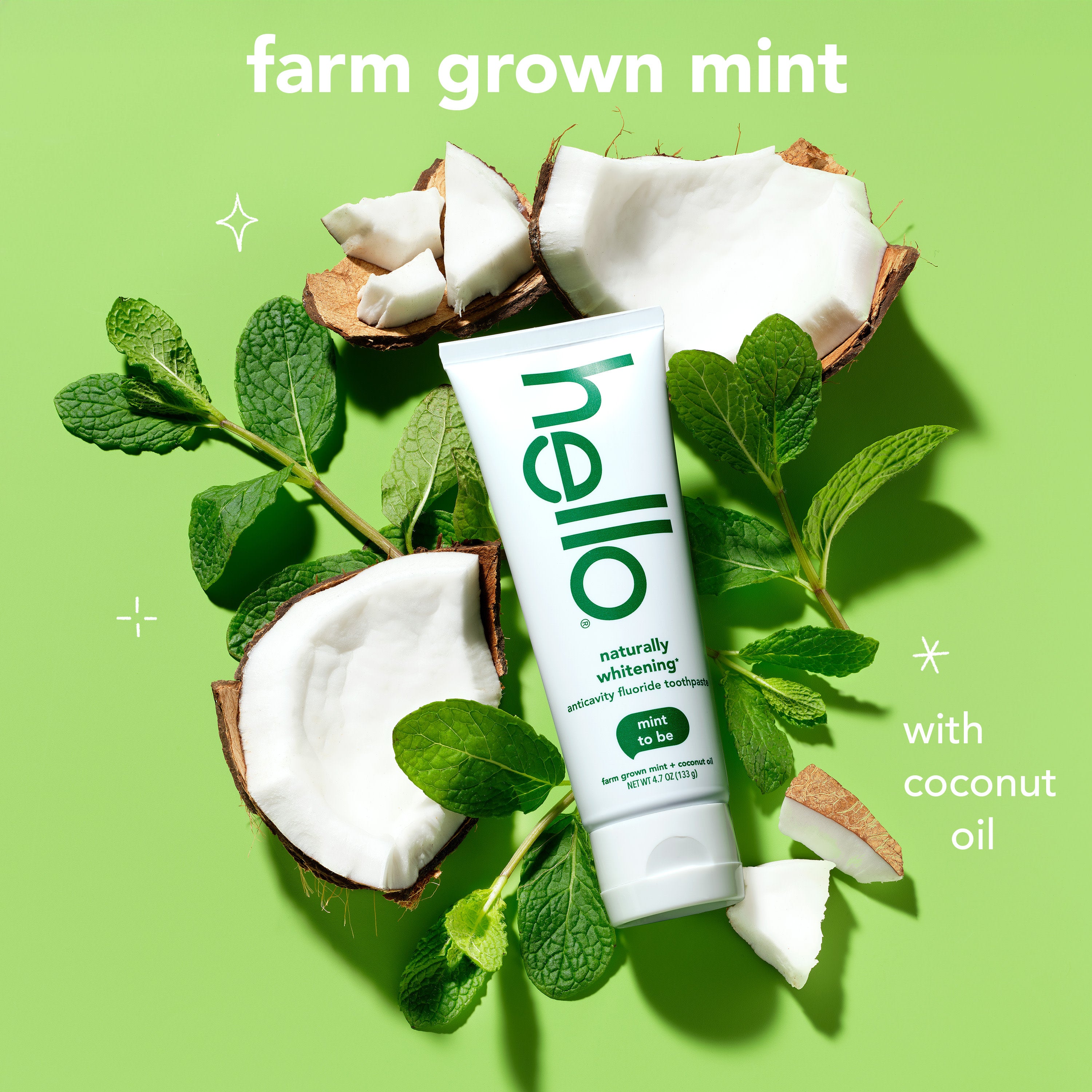 hello Naturally Whitening Anticavity Fluoride Toothpaste against a background of coconut pieces and mint leaves. In text: Farm grown mint with coconut oil.