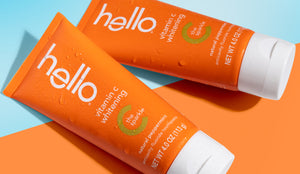 Two 'hello' vitamin C whitening toothpaste tubes on an orange background